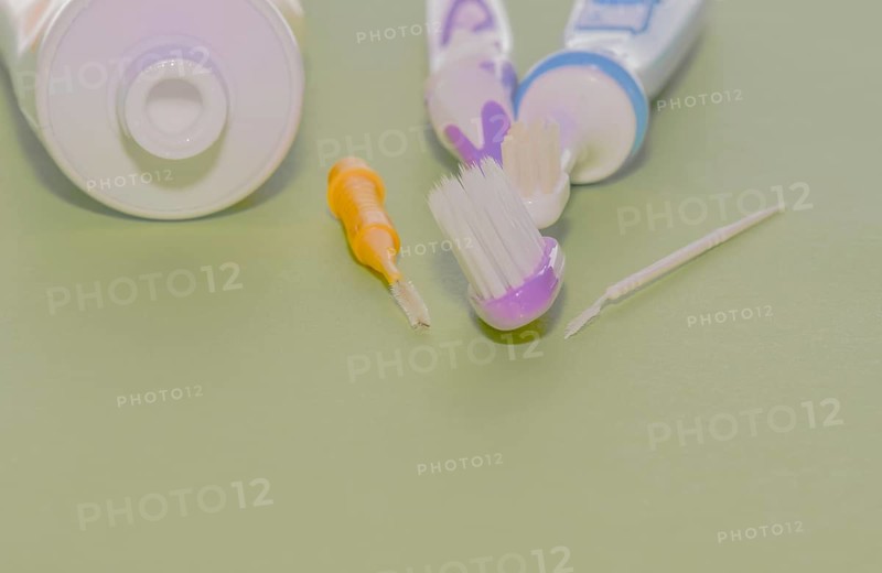 Closeup of toothbrushes and flossing picks next to opened tube of toothpaste