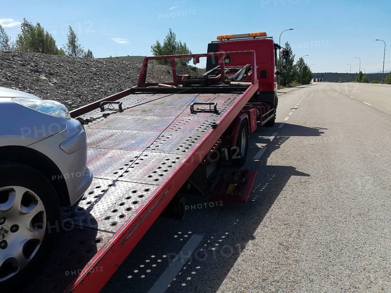 Detail of a tow truck towing a damaged car in the middle of the street