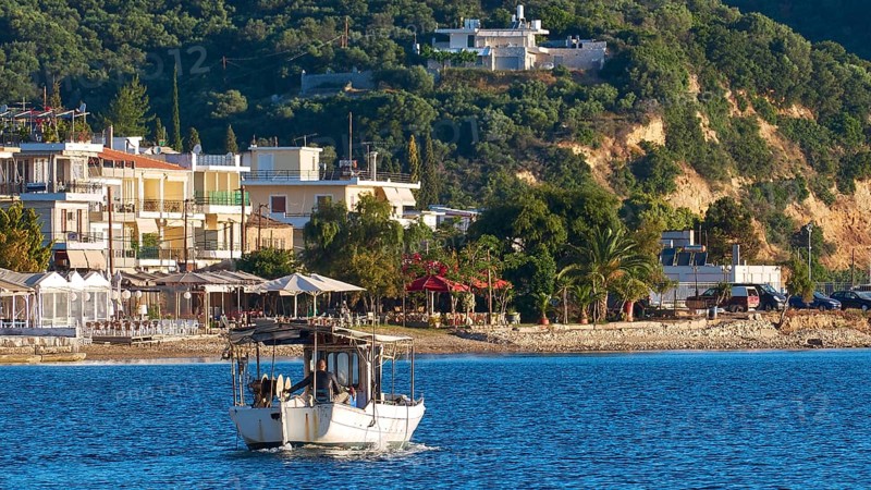 Fishing boat on an idyllic Mediterranean coast with town and hills in the background, Gythio, Mani, Peloponnese, Greece, Europe