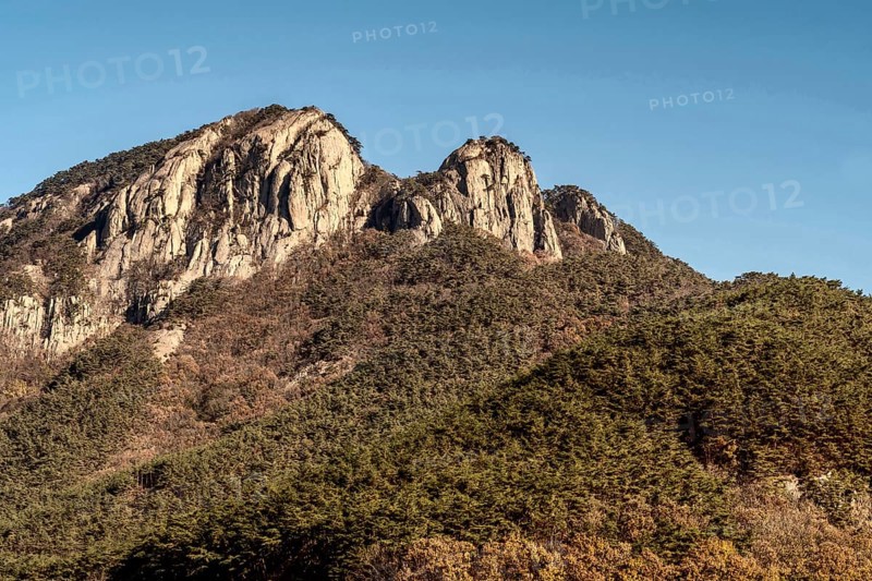 Landscape of tree cover mountain with peak of granite set against clear blue sky in South Korea