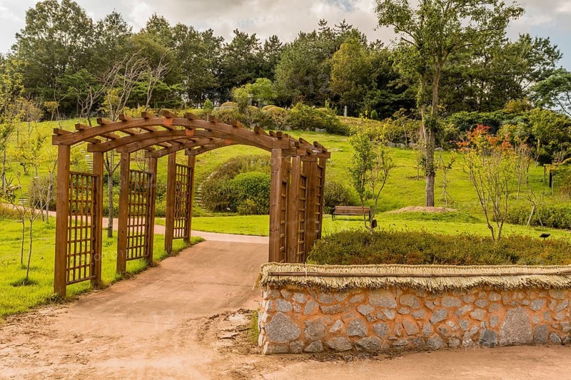 Wooden trellises over concrete walkway in urban park on sunny day in South Korea