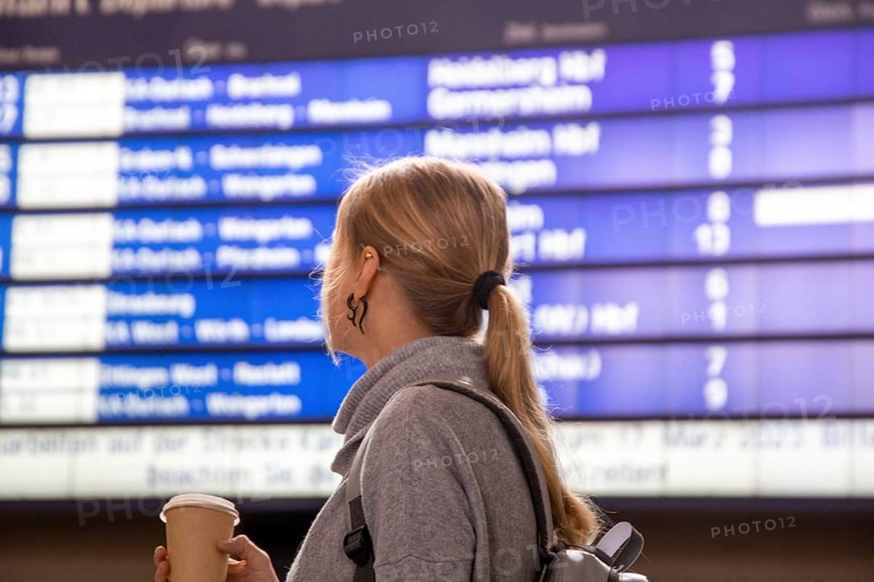 Young woman looking at the scoreboard in a railway station