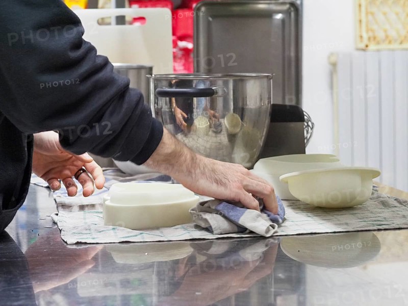 Person cleaning a countertop next to bowls and a blender in a kitchen environment