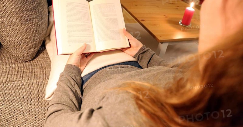 Woman comfortably reading a book on the sofa