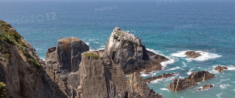 Rocky rugged coastline near Azenha do Mar, Alentejo Littoral, Portugal, southern Europe with white storks (Ciconia ciconia) nesting on cliffs, the only place in the world where they nest on the coastWaves breaking on dramatic rocky, Europe