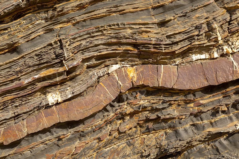 White veins of quartzite forming dykes crossing layers of metamorphosed sedimentary rock in the coastal cliff on the Atlantic coast at Odeceixe, Algarve, Portugal, southern Europe, Europe