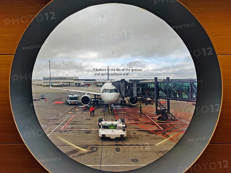 View from a round window of an aeroplane on the tarmac with a printed phrase at Keflavik International Airport, Iceland, Europe