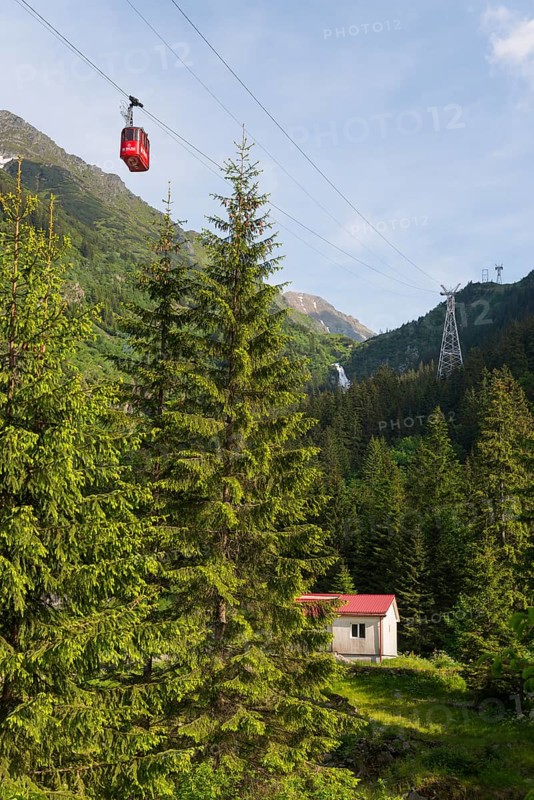 Small cable car gondola crosses a picturesque mountain landscape with fir trees and a small hut and the Balea waterfall, Balea Cascada cable car station, Transfogarasan High Road, Transfagarasan, TransfagaraÈ™an, FagaraÈ™ Mountains, Fagaras, Transylvania, Transylvania, Transylvania, Ardeal, Transylvania, Carpathians, Romania, Europe