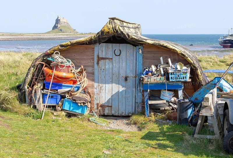 Old upturned boat used as store shed for fishing equipment, Holy Island, Lindisfarne, Northumberland, England, UK