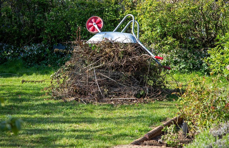 Pile garden waste held down by metal wheelbarrow, collections suspended due to Coronavirus Covid 19, Suffolk, England, United Kingdom, Europe