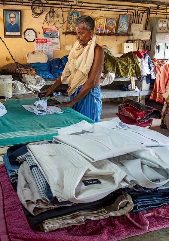 A man irons shirts with an antique iron at Dhobi Khana Public Laundry, Fort Kochi, Cochin, Kerala, India, Asia