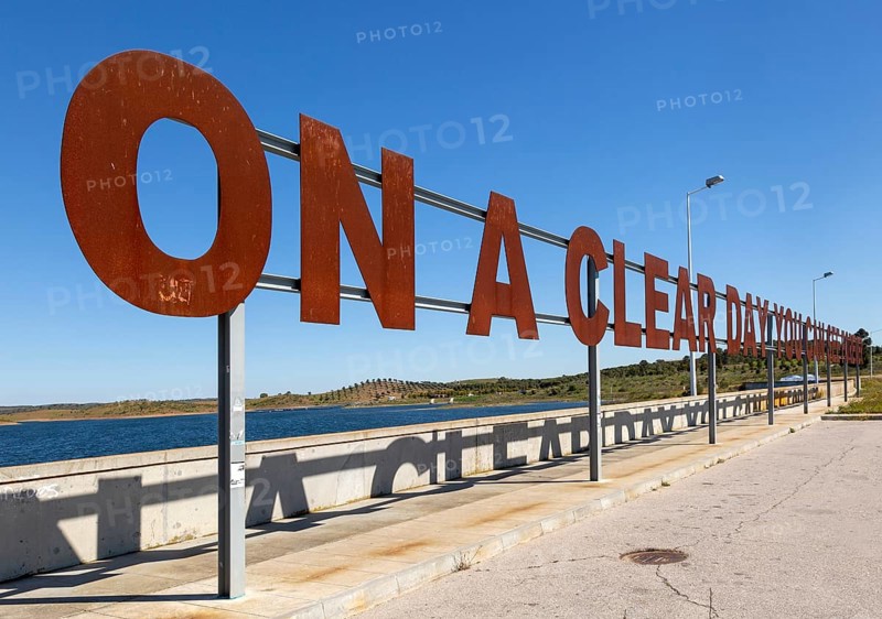 Large red rusty capital letters ON A CLEAR DAY YOU CAN SEE FOREVER blue sky background, Alqueva dam, Moura, Portugal, Europe