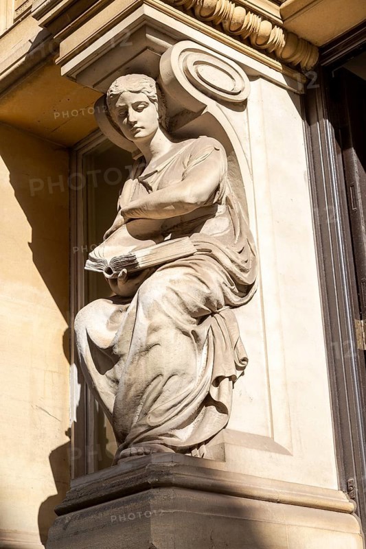 Victorian sculpture of woman reading a book outside old library building in city centre, Cardiff, South Wales, UK