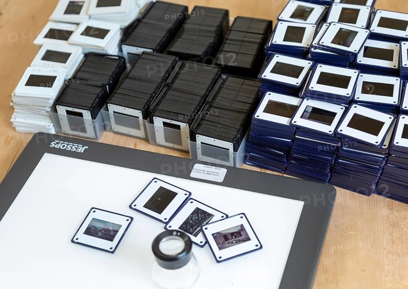 Piles of film transparency slides and Lightbox with viewing enlarger loupe