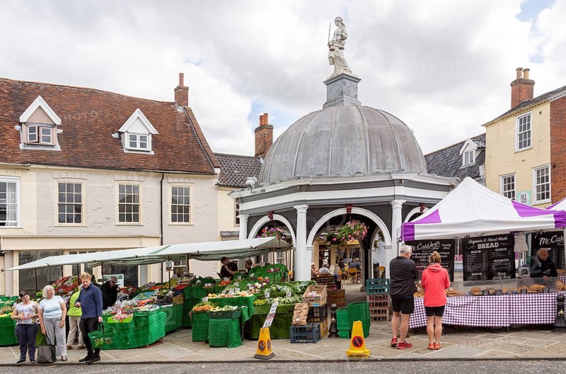 People shopping at market stalls by the Buttercross, Bungay, Suffolk, England, UK