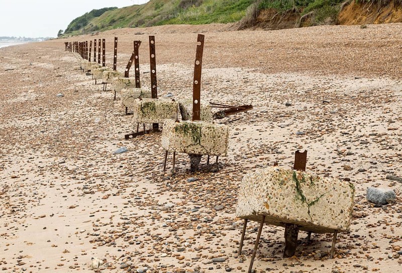 Remains of steel stanchions for barbed wire anti-invasion defences on beach at Bawdsey, Suffolk, England, UK