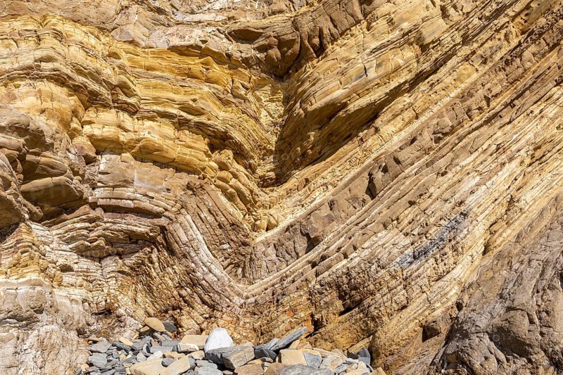 Strata of sandstone sedimentary rock in a coastal cliff with layers folded down to form a geological structure called a syncline, near Zambujeiro do Mar, Alentejo Littoral, Portugal, southern Europe. A syncline is a trough or fold of stratified rock in which the strata slope upwards from the axis. Folds typically form during crustal deformation as the result of compression that accompanies orogenic mountain building, Europe