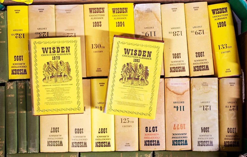 A box of Wisden Cricket almanack books on display in house clearance auction sale room, UK