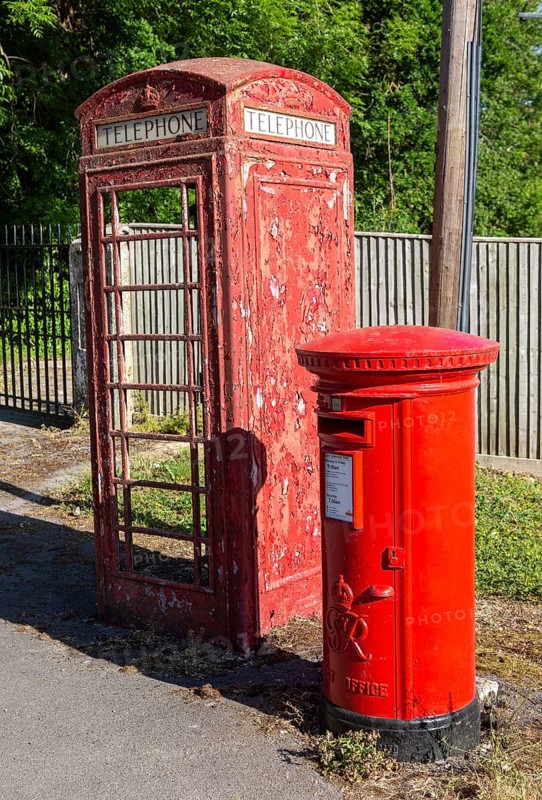 Disused vandalised red telephone box next to smart Royal Mail letter box, UK