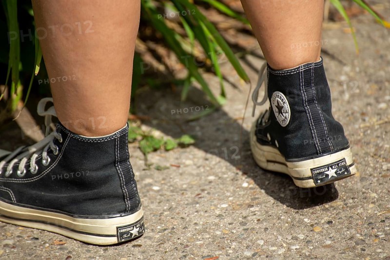 Close-up of black Chucks, worn by a young woman