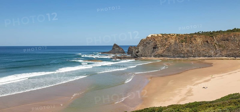 Coastline view of headlands and bay with wide sandy beach, surfer and a few sunbathers, Praia de Odeceixe, Algarve, Portugal, Southern Europe, Europe