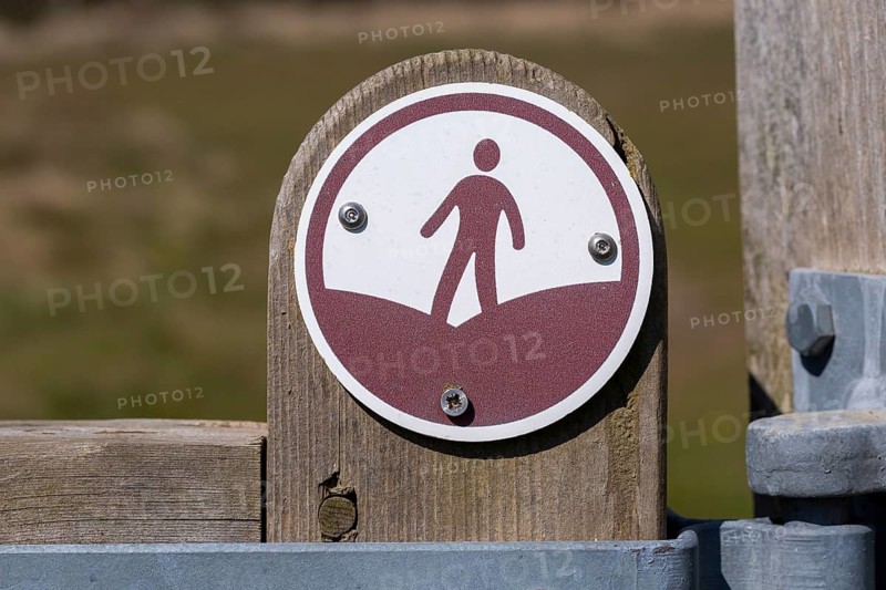 Macro close up of figure walking footpath sign on fencepost, Sutton, Suffolk, England, UK