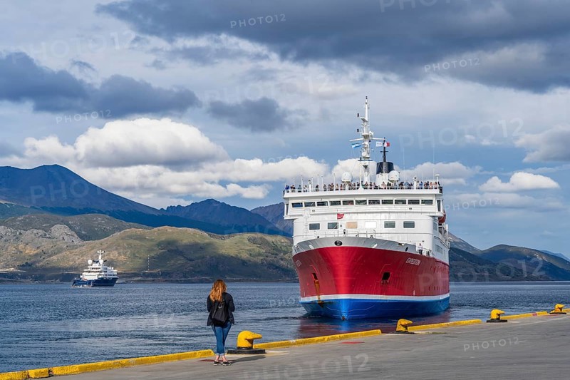 A woman watches a cruise ship named Expedition depart from the harbour of the Beagle Channel, Ushuaia, Tierra del Fuego Island, Patagonia, Argentina, South America