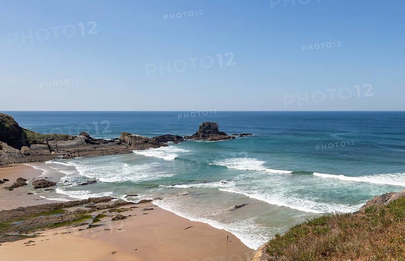 Sandy Carvalhal beach in bay between rocky headlands at Parque Natural do Sudoeste Alentejano e Costa Vicentina, Costa Vicentina natural park, near Brejao, south west Alentejo, Alentejo Littoral, Portugal, Southern Europe. One small figure of a person is visible standing on the shoreline, Europe