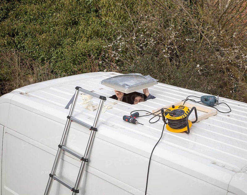 Cutting through roof of white metal camper van conversion to install ventilation window, UK