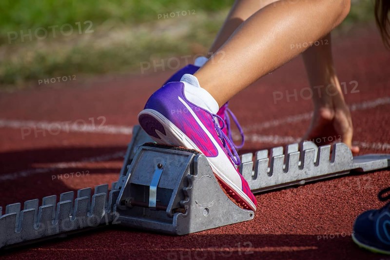 Young track and field athlete with Cougar spikes at the starting block in front of a sprint