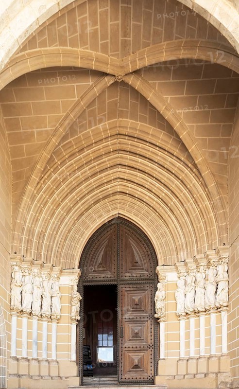 Historic Roman Catholic cathedral church of Evora, Se de Evora, in the city centre, Basilica Cathedral of Our Lady of Assumption. This image shows details of the carved Gothic period main doorway entrance with carved Apostles either side of the door. The arched ogive or ogival arch is considered a masterpiece of Portuguese Gothic art