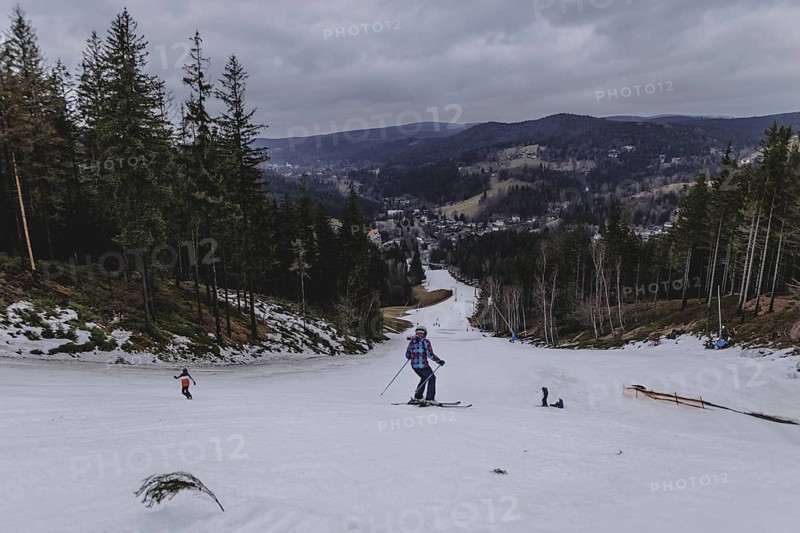 Skiers skiing on an artificially snow-covered and dirty slope, taken on a ski slope in the Jizera Mountains ski area near Albrechtice v Jizerskych Horach, 05.02.2024. The Czech low mountain range with its ski area is affected by increasingly warmer and shorter winters