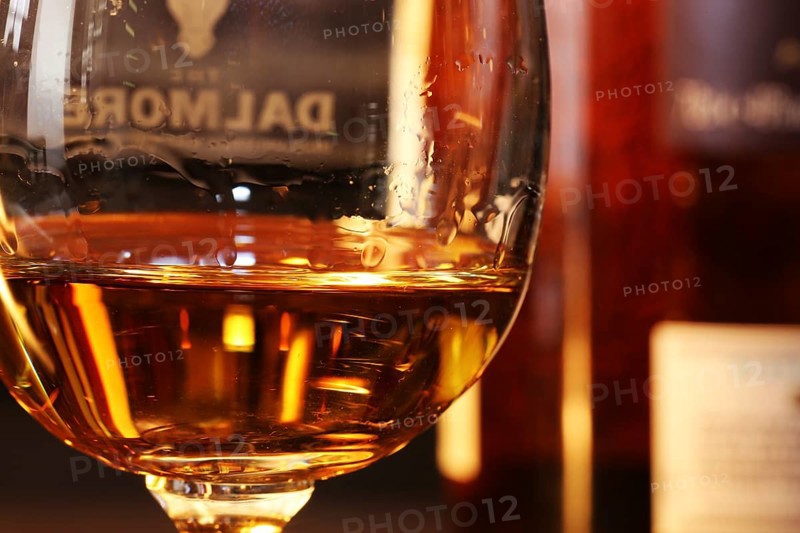Close-up of a glass of whiskey with a bottle of Dalmore single malt in the background