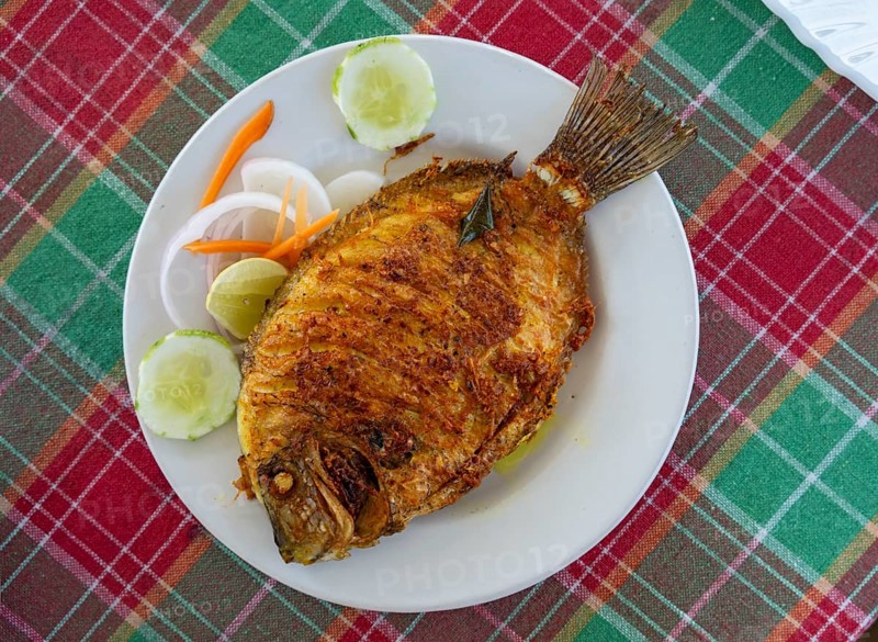 A traditional Kerala fried fish dish, the Pearl Spot (Etroplus suratensis), locally known as â€œKarimeen, â€ served on a plate, India, Asia