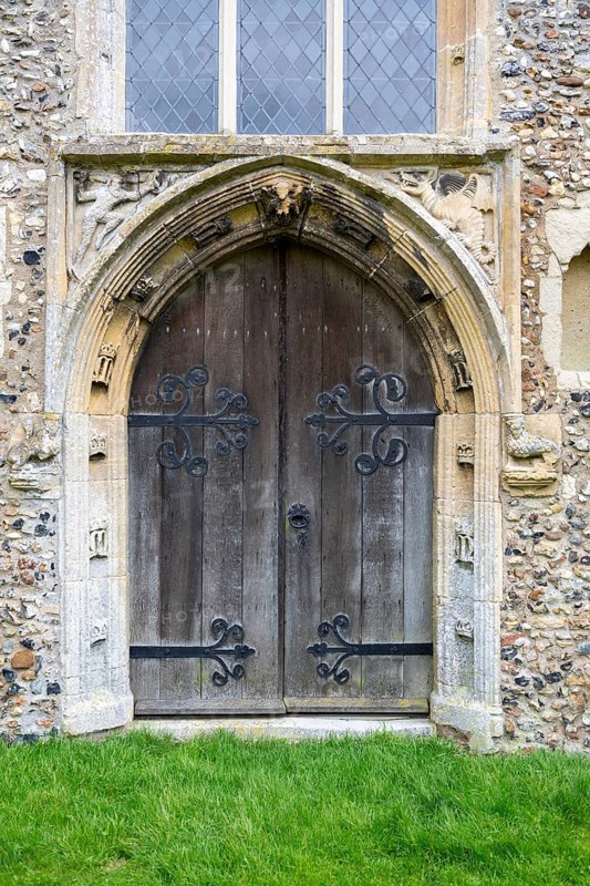 West door Cratfield village parish church, Suffolk, England, UK with spandrel figures of woodwose and wyvern