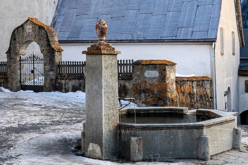 Stone fountain in front of the church, Guarda, Engadin, Grisons, Switzerland, Europe
