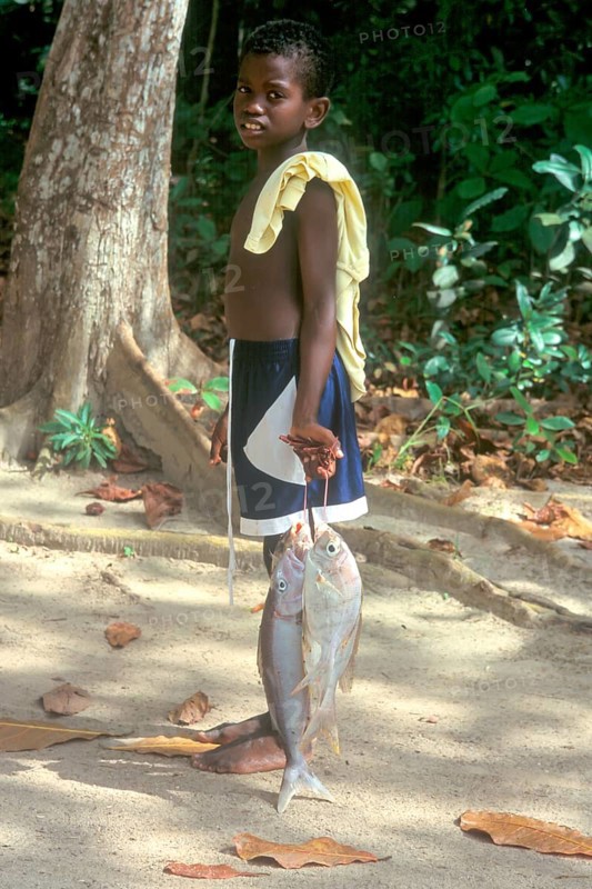 Young carrying fish on the island of La Digue, Seychelles, Africa