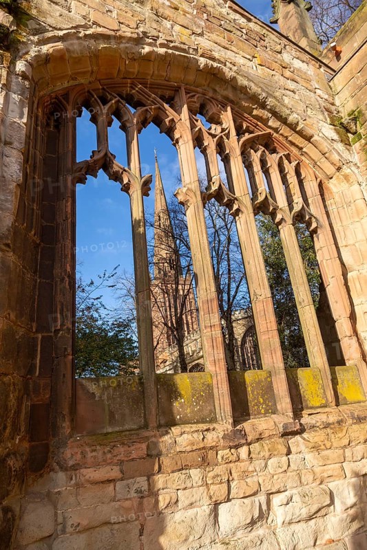 Steeple of Holy Trinity church seen through bombed out windows of old cathedral, Coventry, England, UK