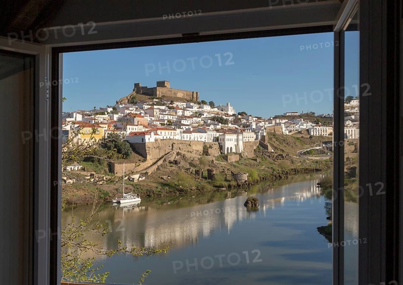 Historic hilltop walled medieval village of Mertola with castle, on the banks of the river Rio Guadiana, Baixo Alentejo, Portugal, Southern Europe framed by hotel window, Europe