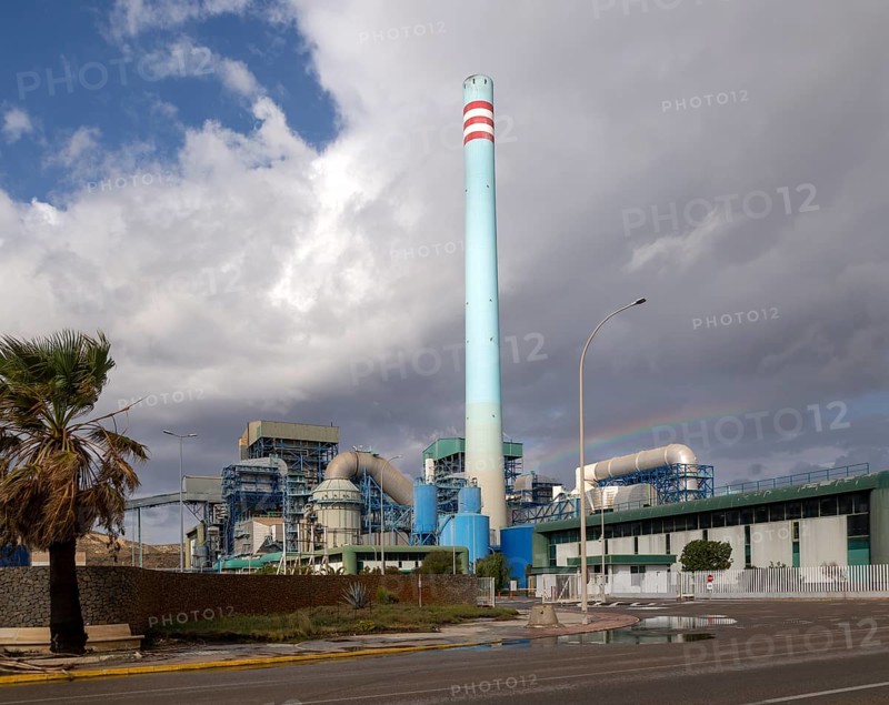 Rainbow in stormy sky behind tall blue industrial cement factory chimney, Carboneras, Almeria, Spain, Europe