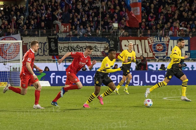 Football match, Lennard MALONEY 1.FC Heidenheim and Jan SCHOePPNER 1.FC Heidenheim left following Youssoufa MOUKOKO Borussia Dortmund on the ball, in the background Emre CAN Borussia Dortmund right, football stadium Voith-Arena, Heidenheim