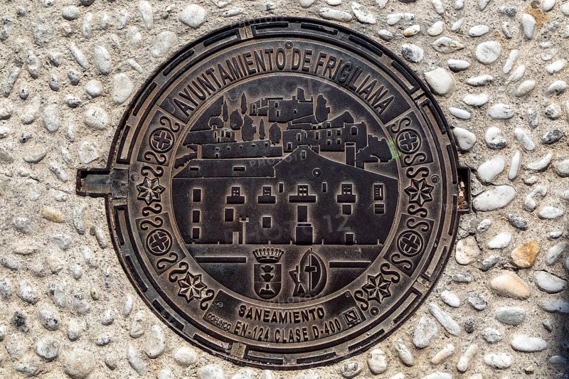 Looking down at metal manhole cover design image of village, Frigiliana, Axarquia, Andalusia, Spain, Europe