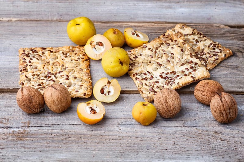 Biscuits with flax, sesame and sunflower seeds and yellow quince fruit on a rustic wooden background