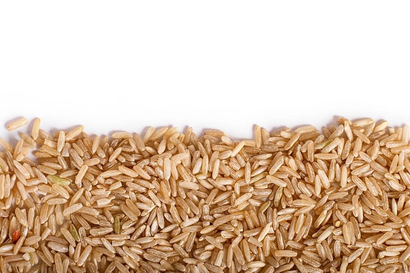 Texture of brown rice isolated on white background. Top view. Copy space