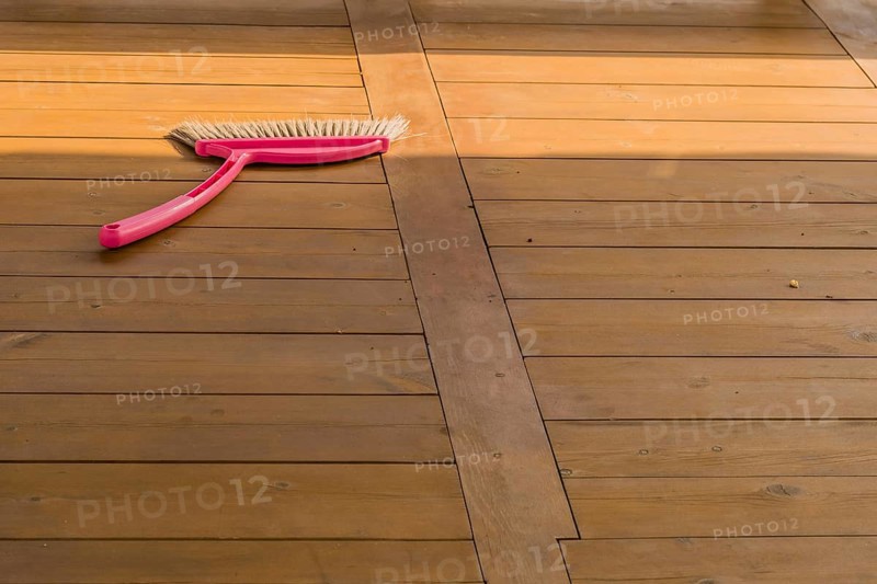 Red plastic broom laying on wooden picnic table in public park in South Korea