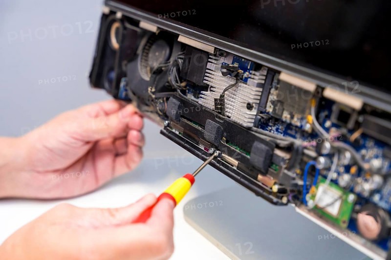 Close-up of an unrecognizable technician fixing computer circuit board of a computer in a workshop