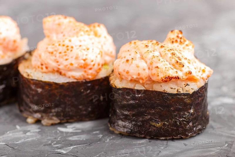 Japanese maki sushi rolls with flying fish roe, cheese on black concrete background. Side view, close up, macro