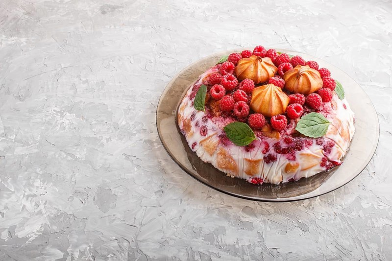 Homemade jelly cake with milk, cookies and raspberry on a gray concrete background. side view, copy space