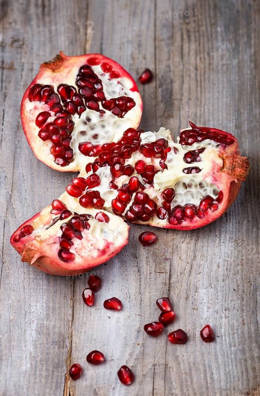 Opened ripe garnet with seeds on a rustic wooden background