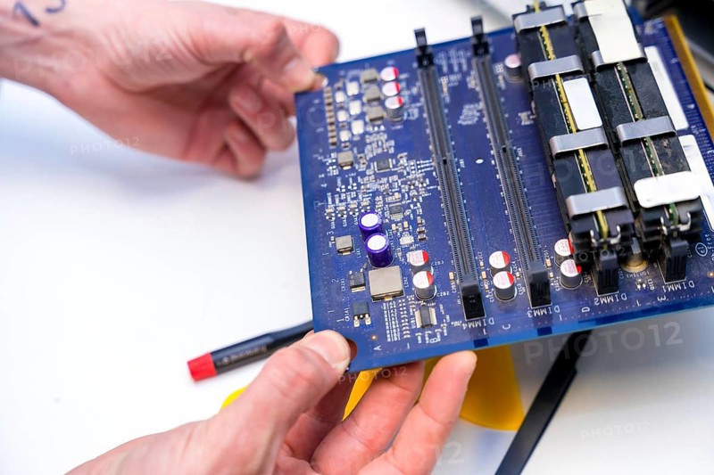 Close-up of the hands of a technician holding an electronic component of computer in a workshop